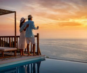 A romantic couple on summer vacation enjos the sunset over the mediterranean sea by the pool with a glass of Aperitif